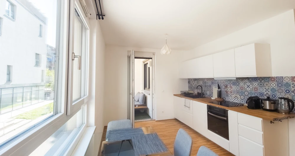 Lisas Inserat auf misterb&b - Heller Essbereich mit großem Fenster und Blick nach draußen. Glas­tisch mit vier Stühlen lädt zu Frühstück, Abendessen und gemütlichen Abenden in ruhiger, moderner Atmosphäre ein.